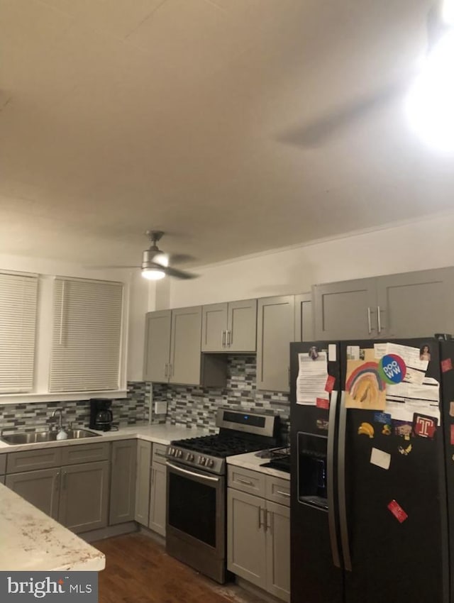 kitchen with tasteful backsplash, sink, black refrigerator with ice dispenser, and stainless steel range with gas stovetop