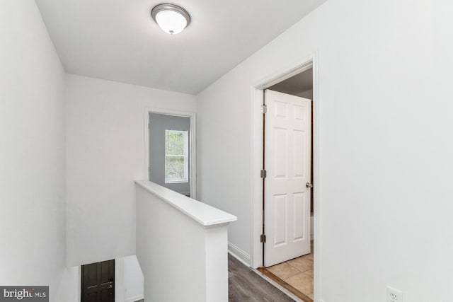 hallway with wood finished floors and an upstairs landing