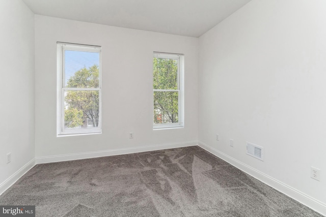 unfurnished room featuring carpet floors, baseboards, visible vents, and a wealth of natural light