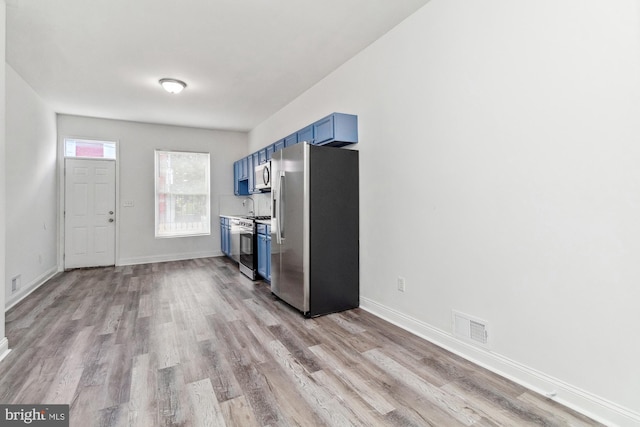 kitchen featuring blue cabinets, stainless steel appliances, and light hardwood / wood-style floors