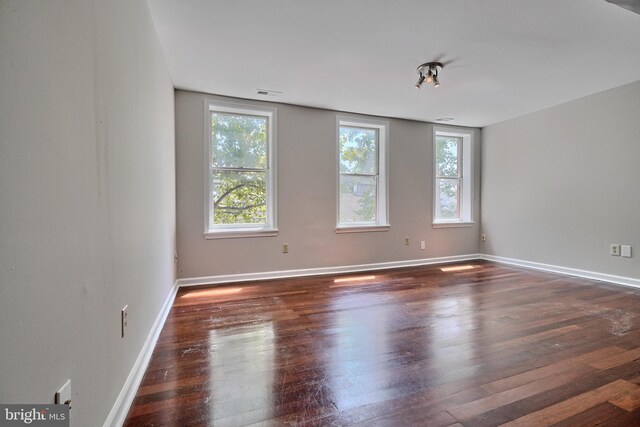 unfurnished room featuring dark hardwood / wood-style flooring and a healthy amount of sunlight