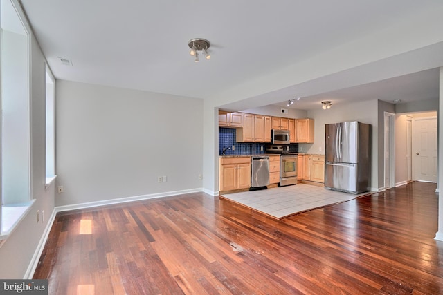 kitchen with appliances with stainless steel finishes, light wood-type flooring, tasteful backsplash, and light brown cabinetry