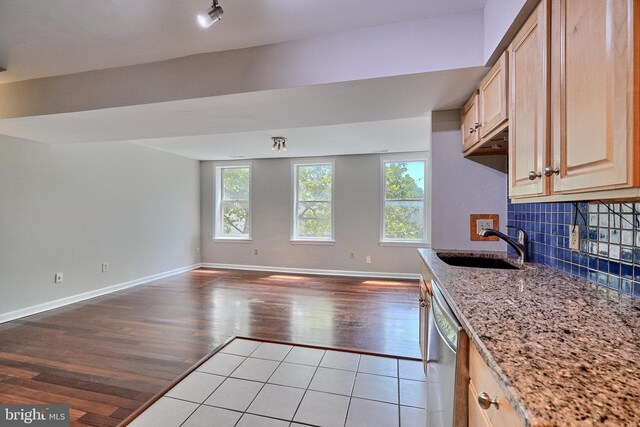 kitchen with light wood-type flooring, sink, tasteful backsplash, stainless steel dishwasher, and light brown cabinets