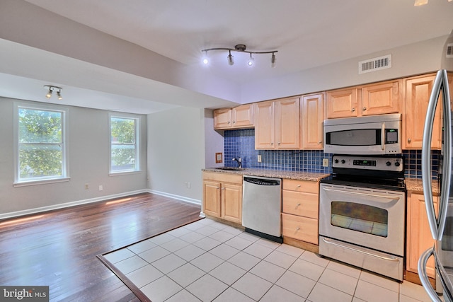 kitchen with light brown cabinetry, appliances with stainless steel finishes, rail lighting, light hardwood / wood-style floors, and sink