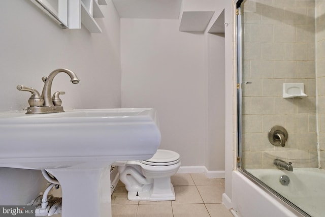 bathroom with tile patterned floors, bath / shower combo with glass door, and toilet