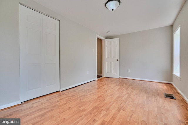 unfurnished bedroom with light wood-type flooring and a closet