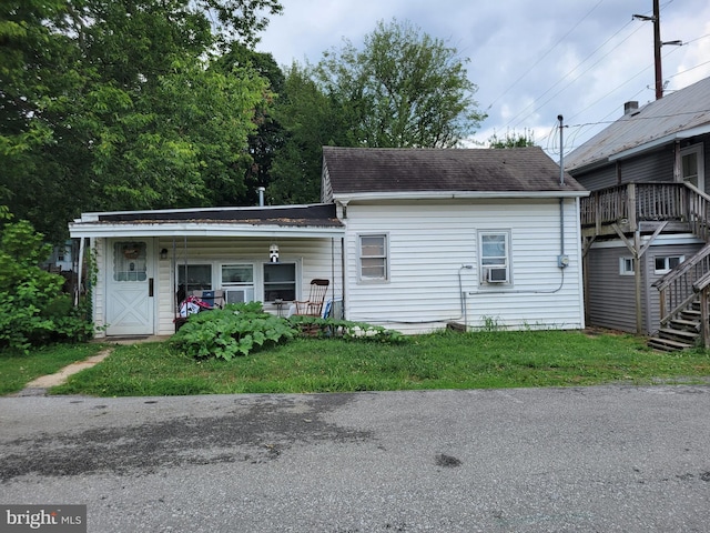 view of front facade featuring cooling unit, covered porch, and a front lawn