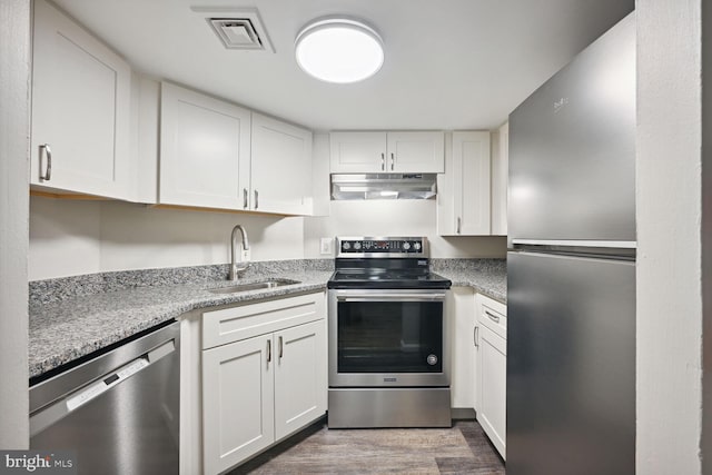 kitchen with stainless steel appliances, light stone countertops, sink, and white cabinets