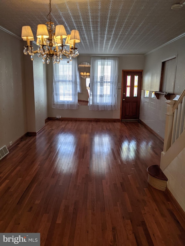 foyer featuring dark wood-type flooring, a notable chandelier, and ornamental molding