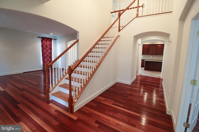 staircase featuring hardwood / wood-style floors and a towering ceiling