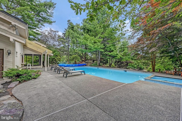 view of swimming pool featuring a patio area and an in ground hot tub