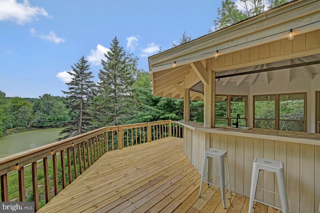 wooden terrace with a water view and a bar