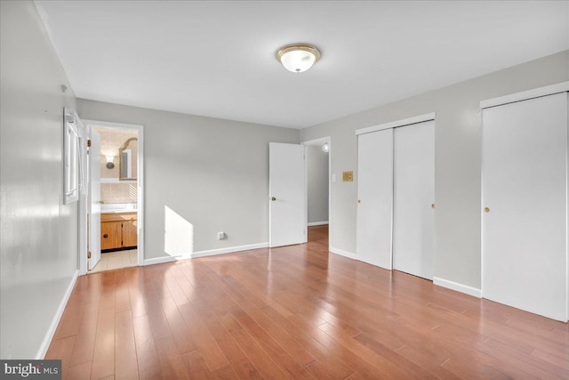 unfurnished bedroom with ensuite bath, multiple closets, and tile patterned floors