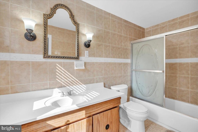 full bathroom with toilet, combined bath / shower with glass door, tile patterned flooring, tile walls, and vanity