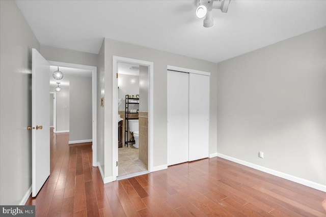 unfurnished bedroom featuring connected bathroom, tile patterned floors, and a closet