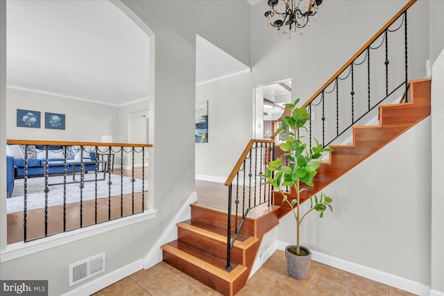 stairway featuring a notable chandelier, ornamental molding, and tile patterned flooring