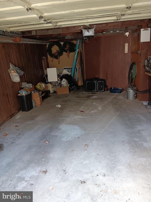 garage featuring a garage door opener and wooden walls