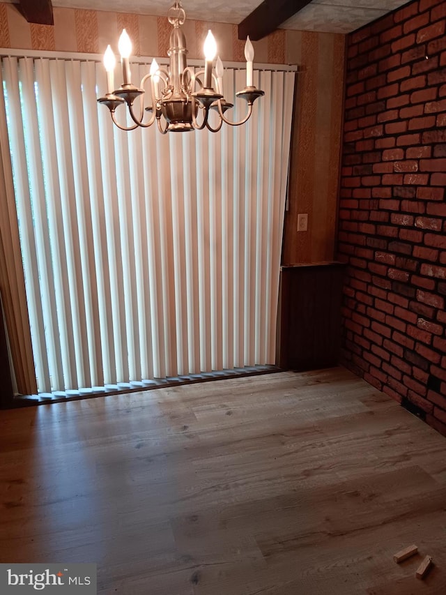 unfurnished dining area with hardwood / wood-style floors, beam ceiling, brick wall, and an inviting chandelier