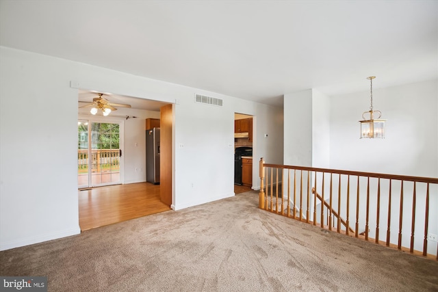 empty room with carpet and ceiling fan with notable chandelier