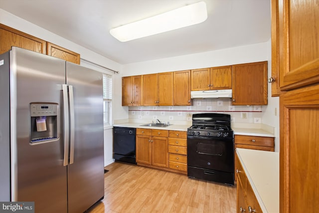 kitchen featuring backsplash, light hardwood / wood-style flooring, black appliances, and sink