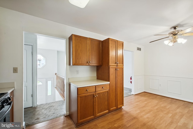 kitchen featuring stainless steel stove, ceiling fan, and light wood-type flooring