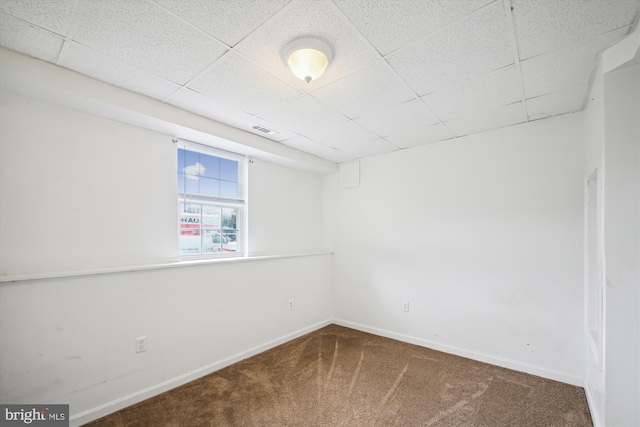 carpeted spare room with a drop ceiling