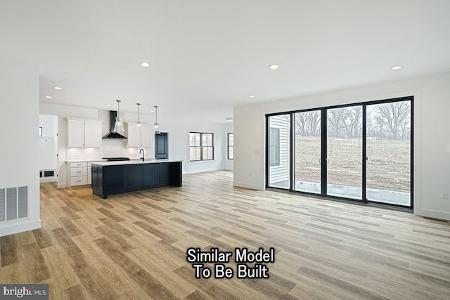 unfurnished living room featuring sink and light hardwood / wood-style flooring