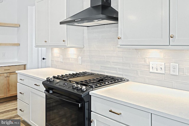 kitchen featuring white cabinetry, light hardwood / wood-style flooring, wall chimney exhaust hood, and gas stove