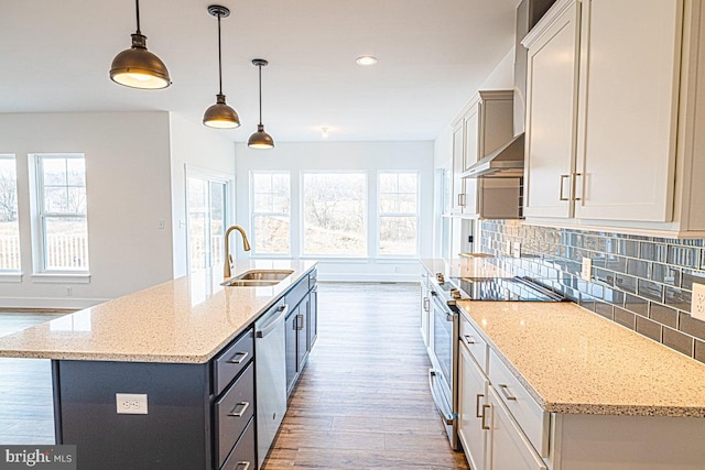 kitchen with pendant lighting, light stone counters, a center island with sink, and sink