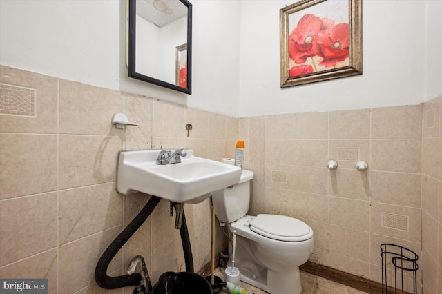 bathroom with toilet and tile walls