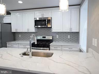 kitchen featuring pendant lighting, stainless steel appliances, and white cabinets