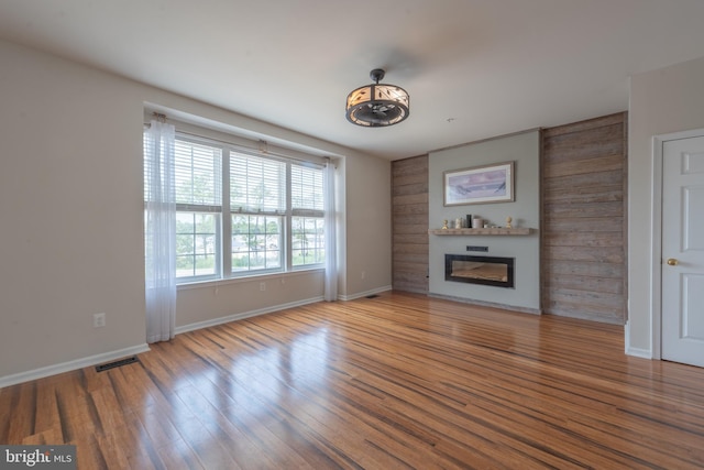 unfurnished living room featuring hardwood / wood-style flooring and wooden walls