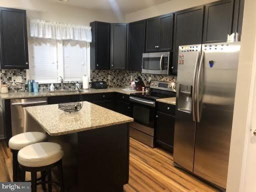 kitchen with sink, stainless steel appliances, a kitchen island, and light wood-type flooring