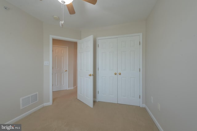 unfurnished bedroom featuring ceiling fan, light carpet, and a closet