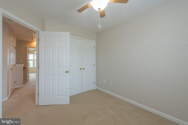 unfurnished bedroom with light colored carpet, a closet, and ceiling fan