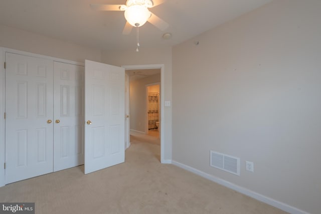 unfurnished bedroom with ceiling fan, light carpet, and a closet