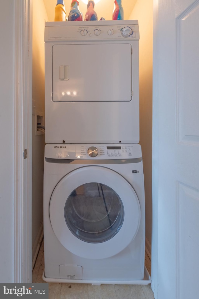 washroom with stacked washer / dryer and light tile patterned floors