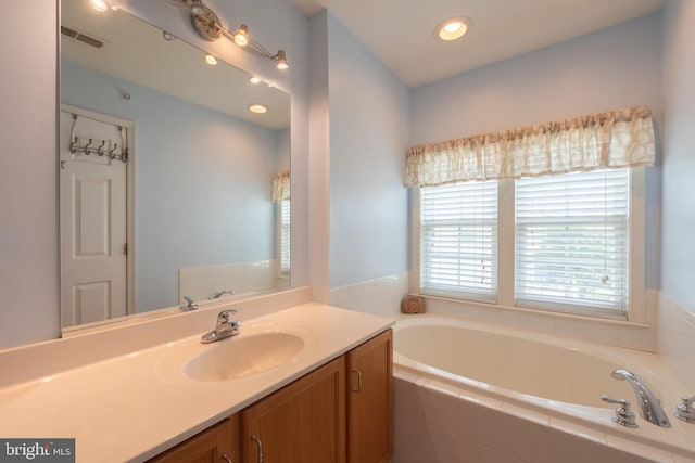 bathroom with tiled tub and vanity