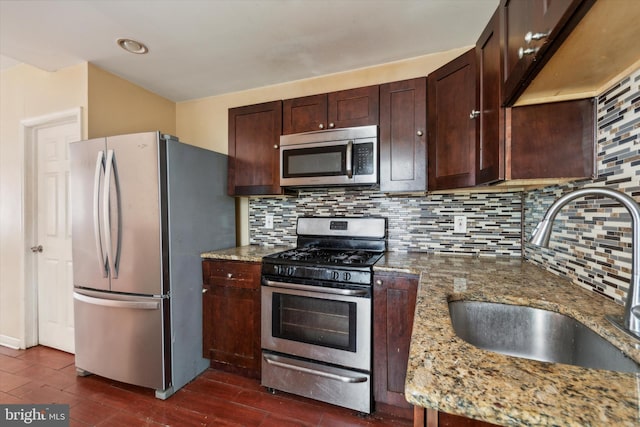 kitchen featuring stainless steel appliances, light stone countertops, sink, and decorative backsplash