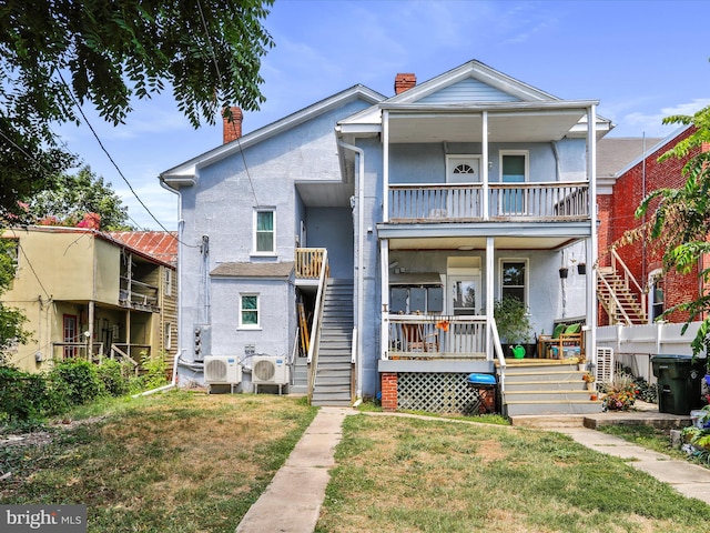 view of front of home with a balcony, a front yard, and ac unit