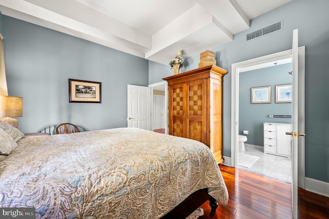 bedroom with ensuite bath and dark wood-type flooring