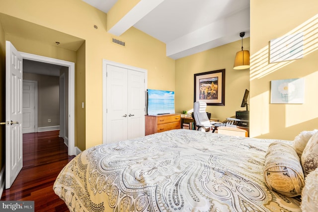 bedroom featuring a closet, beam ceiling, and dark wood-type flooring