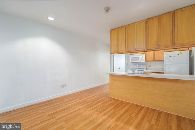 kitchen featuring sink, white appliances, and light hardwood / wood-style floors