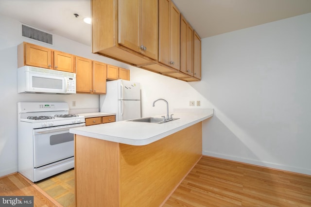 kitchen with sink, white appliances, light hardwood / wood-style flooring, and kitchen peninsula