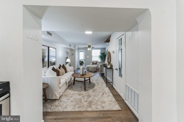 living room featuring ceiling fan and dark wood-type flooring