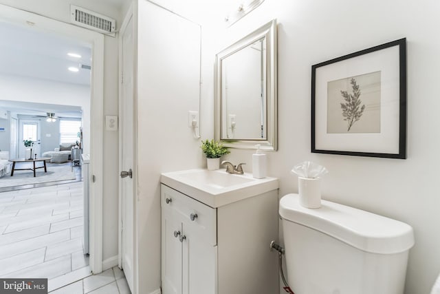 bathroom with toilet, tile patterned floors, vanity, and ceiling fan