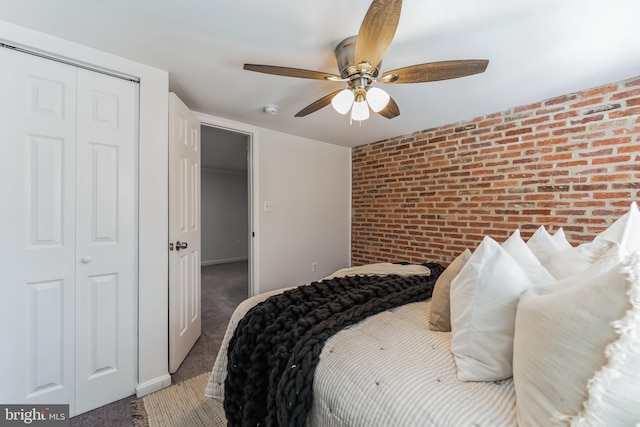 carpeted bedroom with ceiling fan, a closet, and brick wall