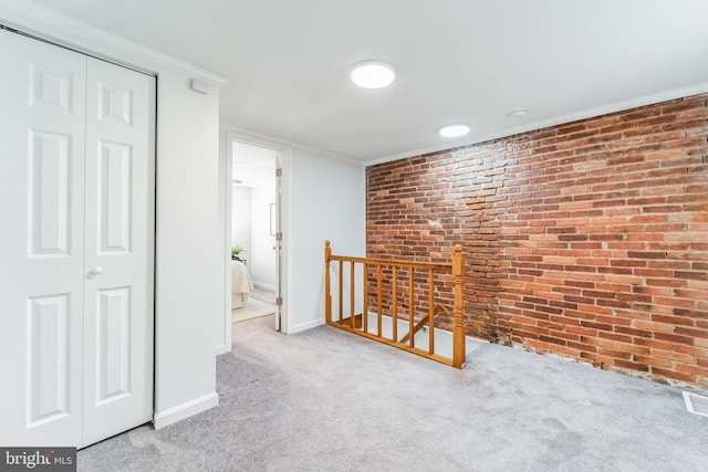 hall featuring ornamental molding, carpet floors, and brick wall