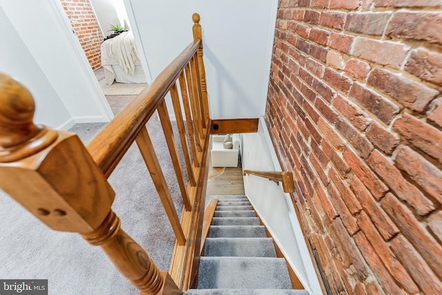 stairs with brick wall and carpet flooring