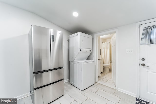 laundry area with light tile patterned flooring and stacked washer / dryer